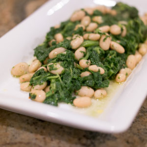 sauteed mustard greens and cannellini beans on a white plate