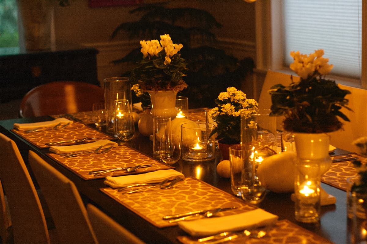 simple dining table set for Thanksgiving dinner - simple white flowers in white vases, white linen napkins, clear glassware, animal print placemats